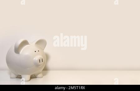 Jolie tirelire en céramique blanche sur fond blanc pour récupérer les pièces de monnaie Banque D'Images