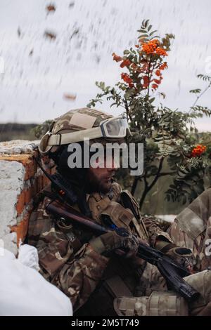 Un défenseur ukrainien lors d'un tir d'artillerie ennemi sur la ligne de front. Guerre entre l'Ukraine et la Russie. Banque D'Images