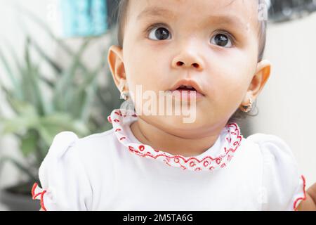 gros plan de la belle petite fille brunette, avec une expression effrayée sur son visage, portant une robe blanche Banque D'Images