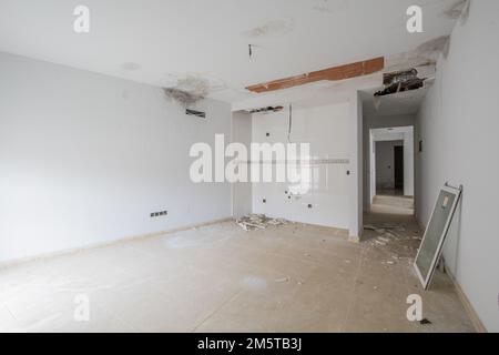 Une pièce vide inachevée avec des carreaux de cuisine sur un mur et de lourds dommages causés par des fuites d'eau Banque D'Images