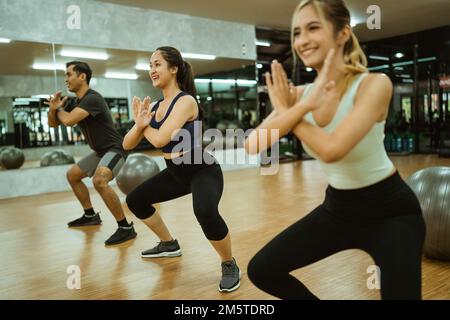 une jeune fille sportive excitée qui se montre bien en forme avec ses amis au centre de fitness Banque D'Images