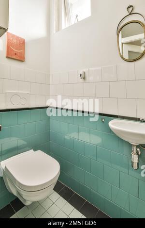 une salle de bains avec des carreaux bleus sur les murs et des accessoires blancs dans la cuvette de toilette est à côté du lavabo Banque D'Images