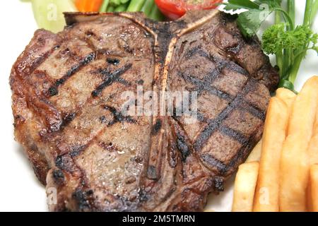 Délicieux bifteck en T grillé avec frites sur fond blanc prêt à servir au restaurant Banque D'Images