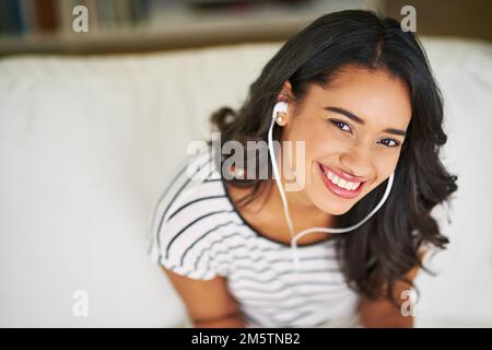 Je suis d'humeur pour la musique. Portrait court d'une jeune femme écoutant de la musique tout en se relaxant sur son canapé à la maison. Banque D'Images