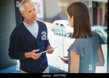 HES un grand mentor. Prise de vue en grand angle de deux collègues ayant une conversation dans leur bureau. Banque D'Images