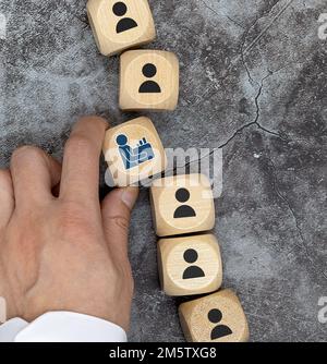 La main masculine met un cube en bois avec le symbole de l'employé à côté du message que nous embauchons. Annonce d'emploi ou de recrutement. Banque D'Images