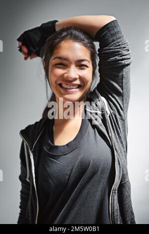 De bonnes choses viennent à ceux qui suent. Portrait d'une jeune femme en forme de vêtements de sport se posant sur un fond gris. Banque D'Images