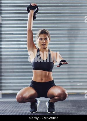 Le corps réalise ce que l'esprit croit. une jeune femme s'entraîner avec des poids à la salle de gym. Banque D'Images