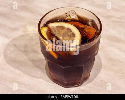 boisson au citron et à la glace au cola ou cocktail au rhum dans un verre teinté rose sur une table en marbre Banque D'Images