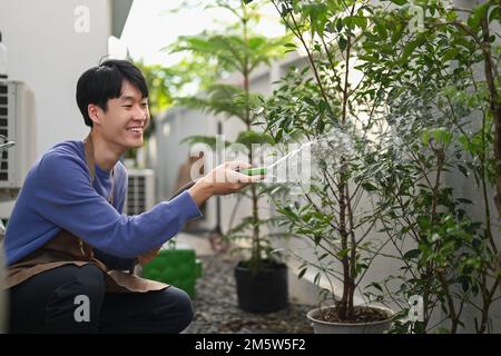 Homme arroser les plantes à l'aide d'un tuyau, en prenant soin des plantes dans le jardin. Jardinage concept de passe-temps Banque D'Images