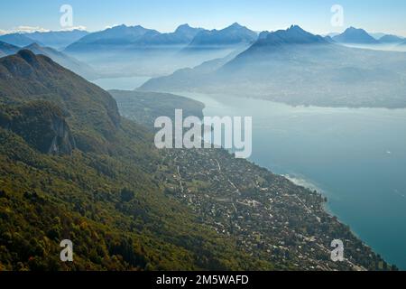 Vue du sommet du Mont Baron sur le village de Veyrier-du-Lac au lac dAnnecy en brume automnale jusqu'à la chaîne des sommets des Alpes savoyardes, Lac de Banque D'Images