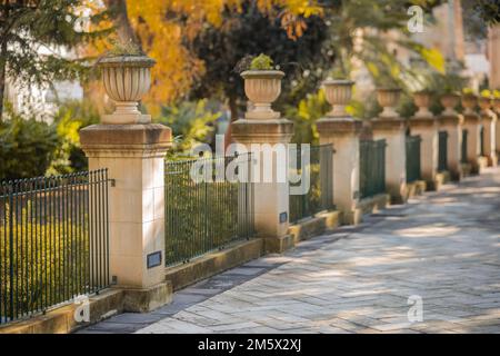 Jardins universitaires d'Argotti à la Valette, Malte, par une journée ensoleillée. Vue sur une rangée de piliers avec clôture. Banque D'Images