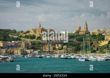 Entrée au port de Mgarr sur l'île de Gozo avec marina visible, églises et bateaux amarrés. Belle ville de bord de mer. Banque D'Images