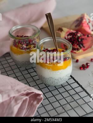 Un petit-déjeuner complet de petits-déjeuners sains avec un mélange de râpe de noix de coco et de purée de mangue, de graines de chia et de grenade Banque D'Images