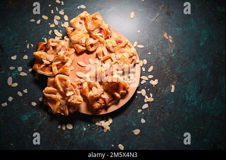 Une vue de dessus de tourtes de pommes décorées avec des amandes sur une planche de bois Banque D'Images