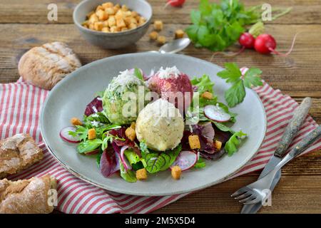 Trio de boulettes traditionnelles du Tyrol du Sud maison, composé des trois différents types d'épinards, de fromage et de betteraves, sur salade de feuilles avec croûtons Banque D'Images