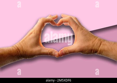 Les mains de l'homme faisant un coeur sur un fond rose. Banque D'Images