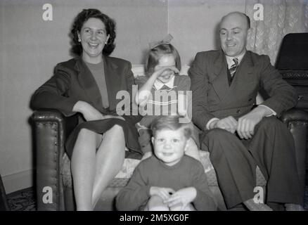 Années 1950, historique, photo de famille, Angleterre, Royaume-Uni, mère et père avec leurs deux jeunes enfants...... publicité fille timide avec sa main sur le visage! Banque D'Images