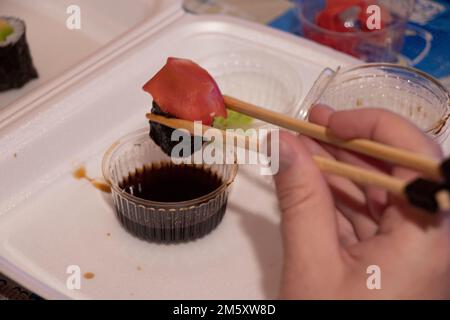 placez les sushis du magasin dans un emballage en plastique sur la table pour le dîner, il y a des sushis à la table à la maison, des emballages en plastique jetables pour les sushis Banque D'Images