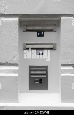 Un cliché vertical en niveaux de gris de boîtes aux lettres et d'intercom dans un vieux mur en plâtre Banque D'Images