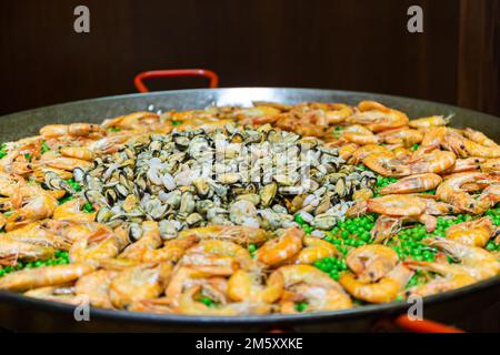 grande poêle à paella avec petits pois et fruits de mer sur la cuisinière Banque D'Images