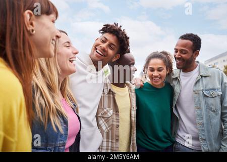 Des jeunes heureux qui marchent et rient. Joyeux groupe d'amis de course mixtes ensemble en plein air. Banque D'Images
