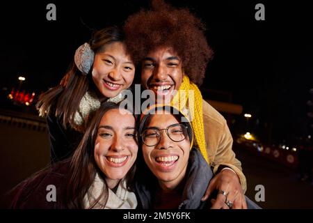 Selfie d'un groupe de personnes heureuses prenant photo selfie dans la nuit avec un téléphone dans des vêtements d'hiver. Banque D'Images