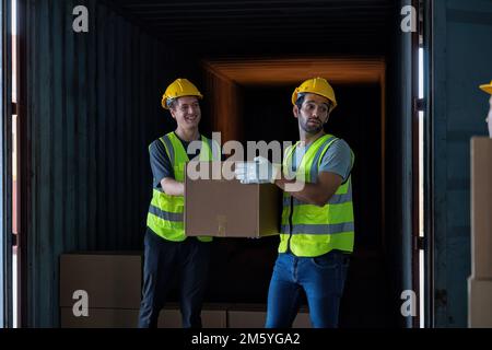 Le travailleur porte une boîte en carton prise dans un conteneur en acier de 40 pieds sur le parking pour camions-remorques à l'entrepôt Banque D'Images