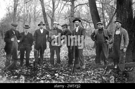 Un groupe de chasseurs se tiennent avec leurs fusils et leur baril de bière, ca. 1920. Banque D'Images