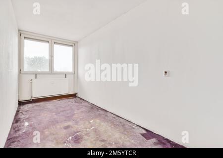 une chambre vide avec des murs blancs et de la moquette violette sur le sol devant une fenêtre donnant sur l'extérieur Banque D'Images