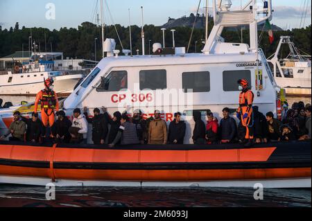 Des membres de la Garde côtière italienne et des migrants vus à bord d'un bateau de patrouille. Près de 90 migrants, principalement d'Afghanistan, du Pakistan et d'Iran, ont été sauvés par la Garde côtière italienne et emmenés au port de Roccella Jonica « Porto Delle Grazie ». Un bébé, né il y a trois jours pendant le passage à niveau, un nouveau-né de 11 jours et un bébé de cinq mois étaient également à bord. Des membres de la Croix-Rouge, des médecins sans frontières et du personnel sanitaire ont aidé les bébés, leurs familles et d'autres migrants. (Photo de Valeria Ferraro/SOPA Images/Sipa USA) Banque D'Images