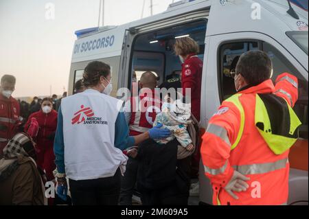 Un membre de Docteur sans frontières a vu parler avec une dame. Près de 90 migrants, principalement d'Afghanistan, du Pakistan et d'Iran, ont été sauvés par la Garde côtière italienne et emmenés au port de Roccella Jonica « Porto Delle Grazie ». Un bébé, né il y a trois jours pendant le passage à niveau, un nouveau-né de 11 jours et un bébé de cinq mois étaient également à bord. Des membres de la Croix-Rouge, des médecins sans frontières et du personnel sanitaire ont aidé les bébés, leurs familles et d'autres migrants. (Photo de Valeria Ferraro/SOPA Images/Sipa USA) Banque D'Images