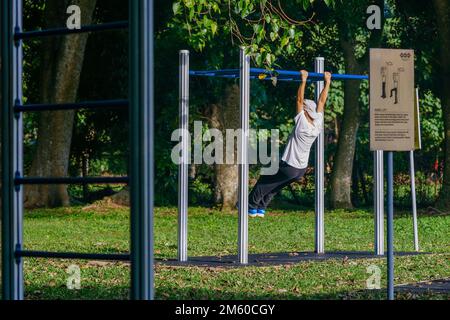 Une personne âgée utilisant de l'équipement d'exercice dans le parc un matin ensoleillé Banque D'Images