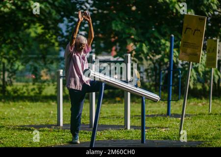 Une personne âgée utilisant de l'équipement d'exercice dans le parc un matin ensoleillé Banque D'Images