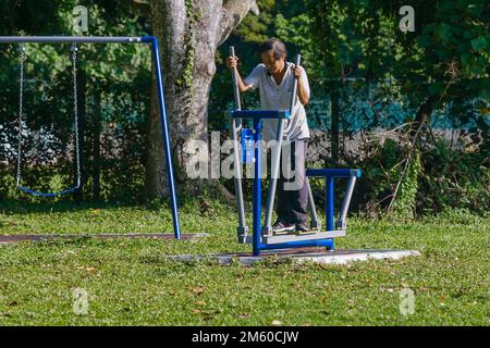 Une personne âgée utilisant de l'équipement d'exercice dans le parc un matin ensoleillé Banque D'Images