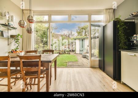 une cuisine et salle à manger dans une maison avec des portes vitrées coulissantes qui s'ouvrent sur le patio de l'arrière-cour, qui est entouré d'arbres Banque D'Images