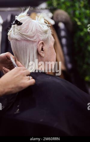 les mains coupent les cheveux de la femme aux cheveux blancs avec de l'espace pour écrire Banque D'Images