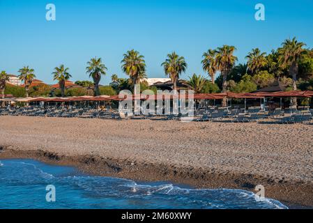 Chaises longues vides et parasols en bois disposés sur une plage de sable Banque D'Images