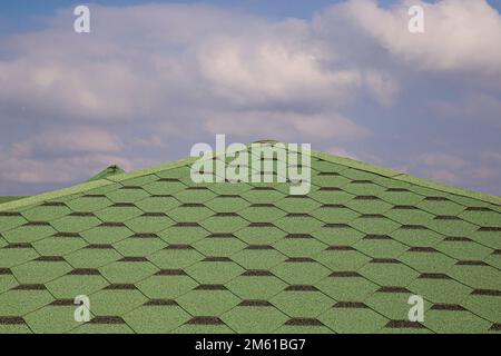 Toiture en carreaux de bitume doux et vert sur un toit ébréché d'une maison. Vue rapprochée de l'arrière-plan de la tuile verte du toitures d'asphalte. Carreaux verts sur le toit Banque D'Images