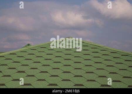 Toiture en carreaux de bitume doux et vert sur un toit ébréché d'une maison. Vue rapprochée de l'arrière-plan de la tuile verte du toitures d'asphalte. Carreaux verts sur le toit Banque D'Images