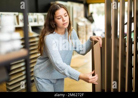 Client féminin détenant des échantillons de panneaux en bois dans le magasin de matériel Banque D'Images