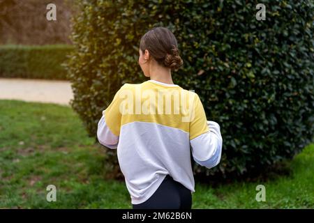 Vue arrière d'une athlète féminine anonyme en plein échauffement avant de s'entraîner dans un sweat-shirt de parc Banque D'Images