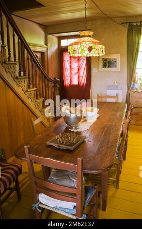 Longue table à manger en bois teinté brun antique et chaises dans la salle à manger avec lampe tiffany colorée à l'intérieur de la vieille maison de 1838 Canadiana Fieldstone. Banque D'Images