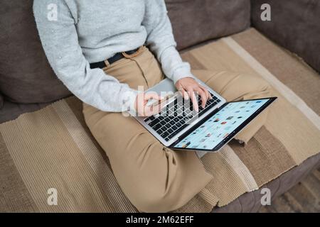 Une femme shopping en ligne tenir la carte de crédit et ordinateur portable main de jeune adulte femme faire l'achat en ligne prendre la décision tout en étant assis à la maison r Banque D'Images