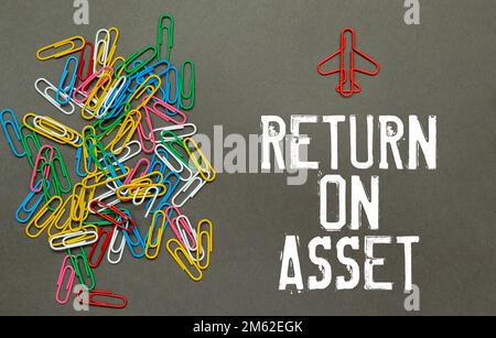 Concept commercial et commercial. Sur le fond du tableau de cotation, un homme tient un signe avec l'inscription - RETOUR SUR L'ACTIF Banque D'Images