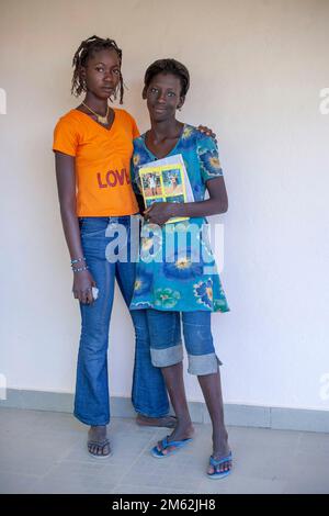 Étudiants. Deux jeunes étudiantes de l'université souriant amical à l'appareil photo, portant des vêtements modernes tenant un livre de note Banque D'Images