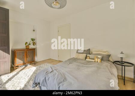 une chambre avec un lit, une commode et un miroir sur le mur en face de la chambre est de couleur très blanche Banque D'Images