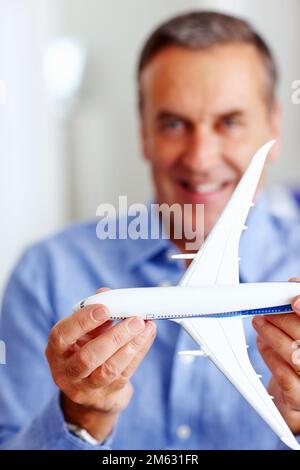 Heureux homme senior tenant un avion jouet devant vous. Gros plan portrait d'un homme senior heureux tenant un avion jouet devant vous. Banque D'Images