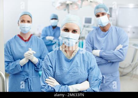 Chirurgiens avec un engagement pour d'excellents soins. Portrait d'un groupe de chirurgiens portant des gommages hospitaliers, des masques et des gants de protection dans un Banque D'Images