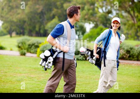 Couple portant des sacs de golf. Couple portant des sacs de golf et regardant l'un l'autre. Banque D'Images